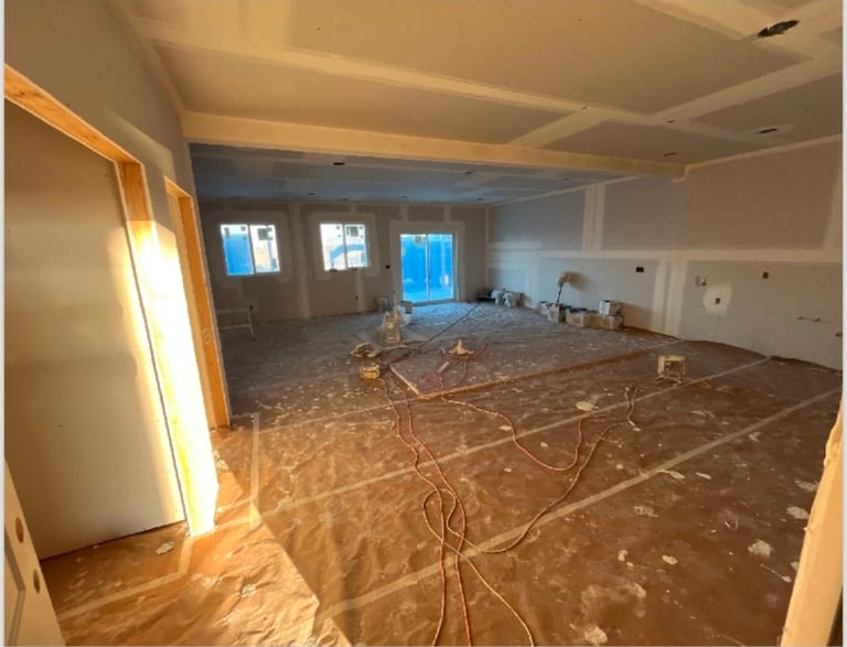 Empty construction room with exposed flooring, electrical wiring, and finished drywall walls and ceiling