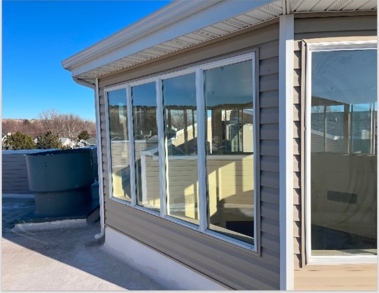 Modern building exterior with large glass windows and sliding glass doors reflecting sunlight on a clear day