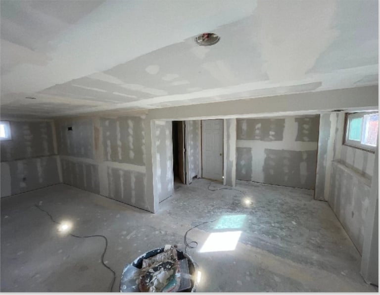 Interior of an unfinished room under construction with drywall, white ceiling, and debris on the floor