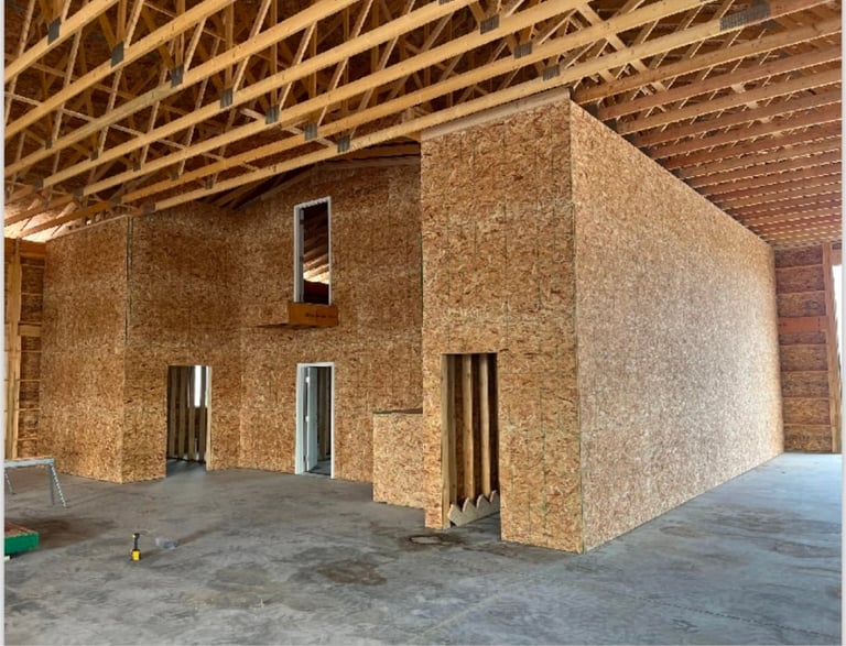 Interior of a building under construction with cork walls, wooden roof frame, and concrete floor